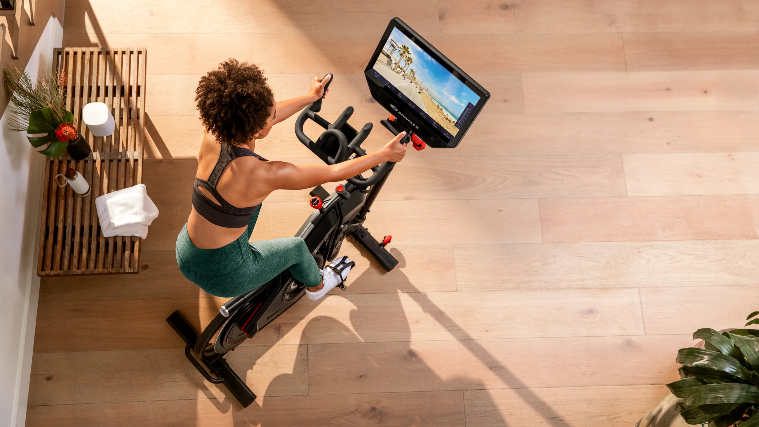 Overhead view of a rider on the VeloCore on a wood floor, screen showing a scenic route